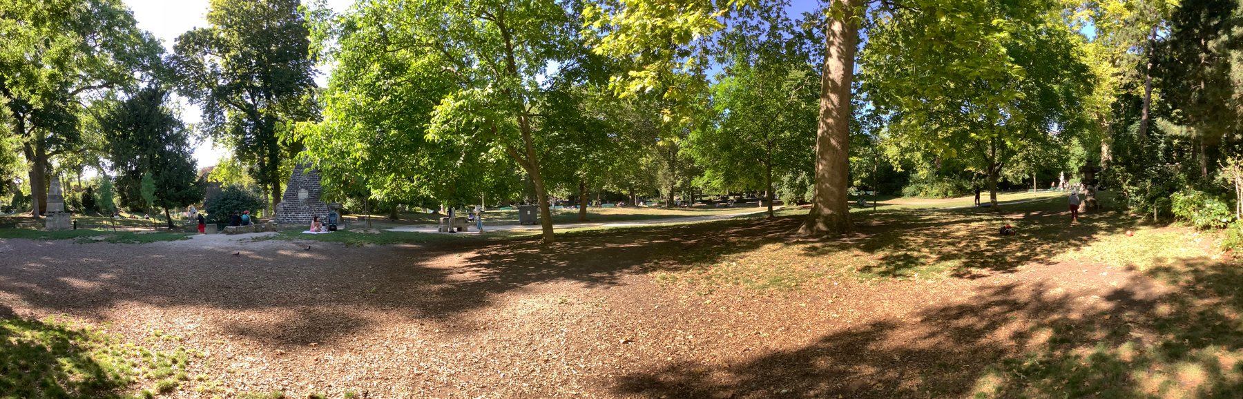 Sunlight through trees beside a path in Parc Monceau, photographed in 2022